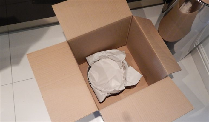 Тарелки и кухонные принадлежности, упакованные в коробку для переезда